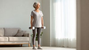 Woman performing dumbbell resistance training as part of osteoporosis prevention exercises at home