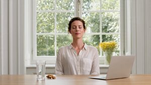 Woman taking a mindful wellness pause at her office desk, representing practical health and wellness tips for employees